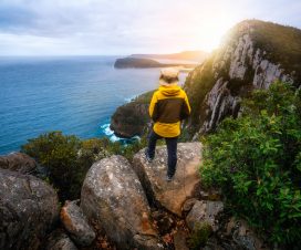 Young man trekker hiking on beautiful coast cliff of Tasman National Park in Tasman peninsula, Three Capes Track near Port Arthur in Tasmania, Australia.
