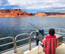 Woman relaxes and enjoys the fantastic views of sandstone cliffs and blue skies. She is on a houseboat on Lake Powell in Arizona. She fishes holding the rod with her toes.