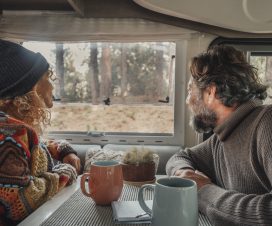 Young mature couple enjoy time inside camper van in van life lifestyle vacation. Travel people concept lifestyle. Admiring freedom nature park outdoors view outside the window. Rv vehicle renting