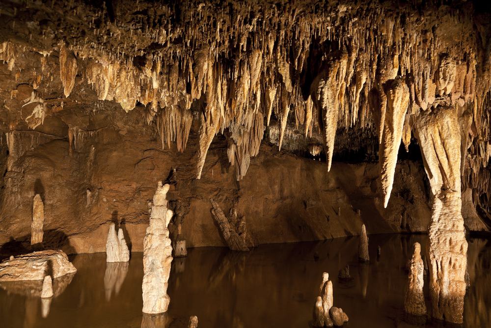 Details within a cave in Meramec Caverns in Stanton Missouri. Stalactite's hang and reflect in the pool of water on the floor of the cave.