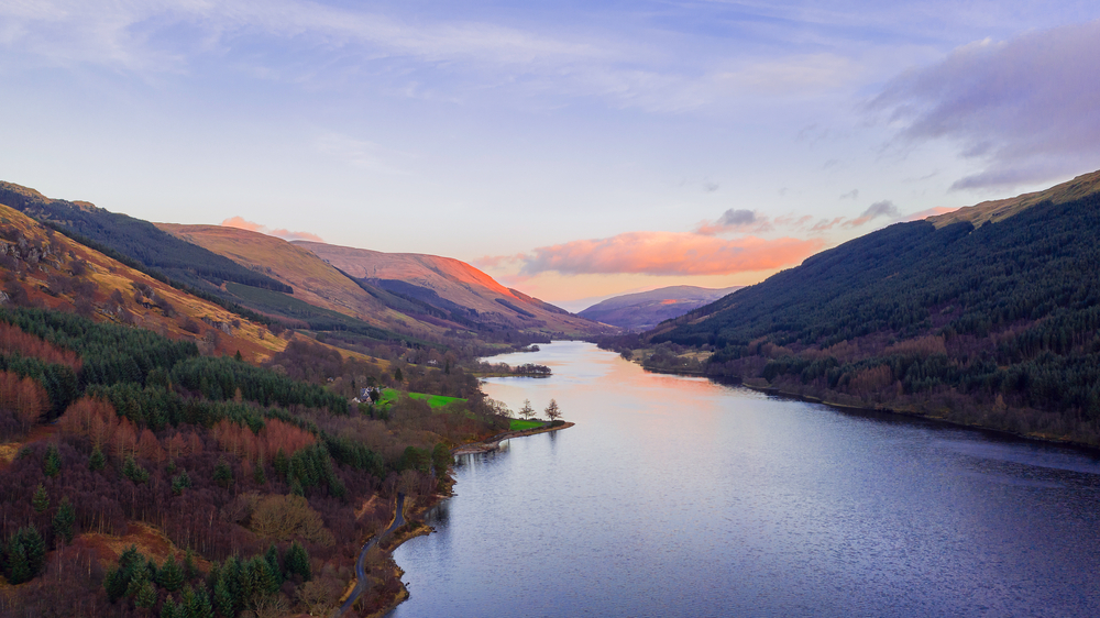 Scottish beautiful colorful sunset landscape with Loch Voil, mountains and forest at Loch Lomond The Trossachs National Park. Nature evening scenery in Scotland over the mountain lake.